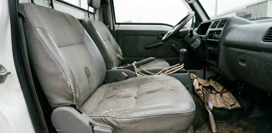 Kei truck interior seat showing wear and tear caused by daily work use including fading, cracks, and fabric damage inside the cabin